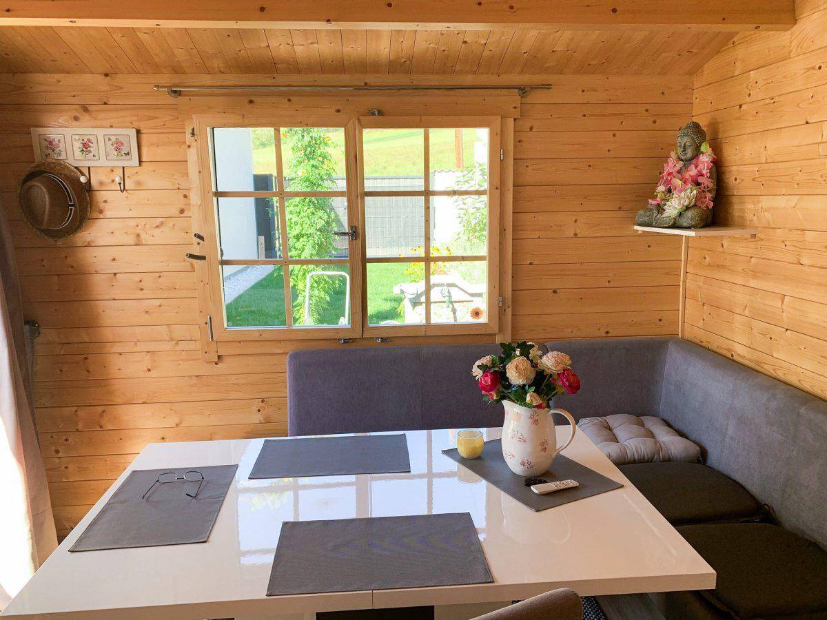 Heller Essbereich im Gartenhaus mit Holzwänden, Eckbank und Blick ins Grüne.