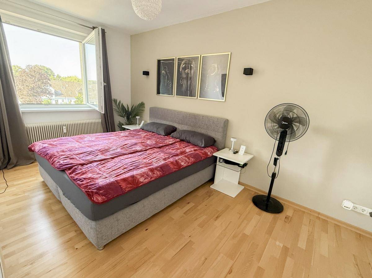 Schlafzimmer mit Doppelbett, Holzfußboden und großem Fenster für viel Tageslicht.
