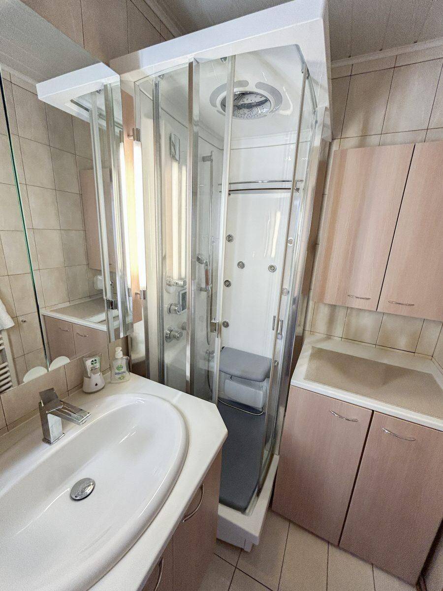 Badezimmer mit Duschkabine, Einzelwaschbecken und hellen Fliesen, funktional und sauber.
