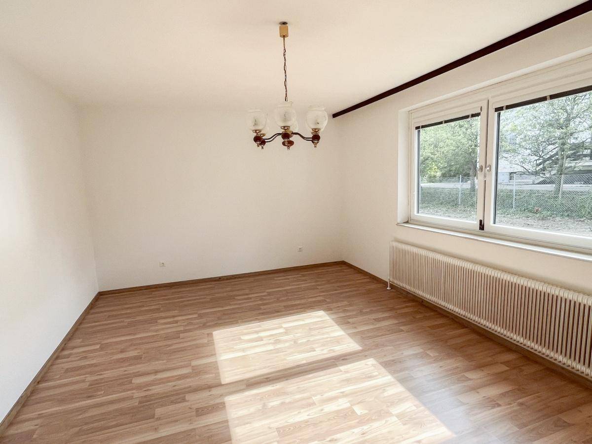 Geräumiges Schlafzimmer mit Laminatboden und viel Tageslicht durch das große Fenster.