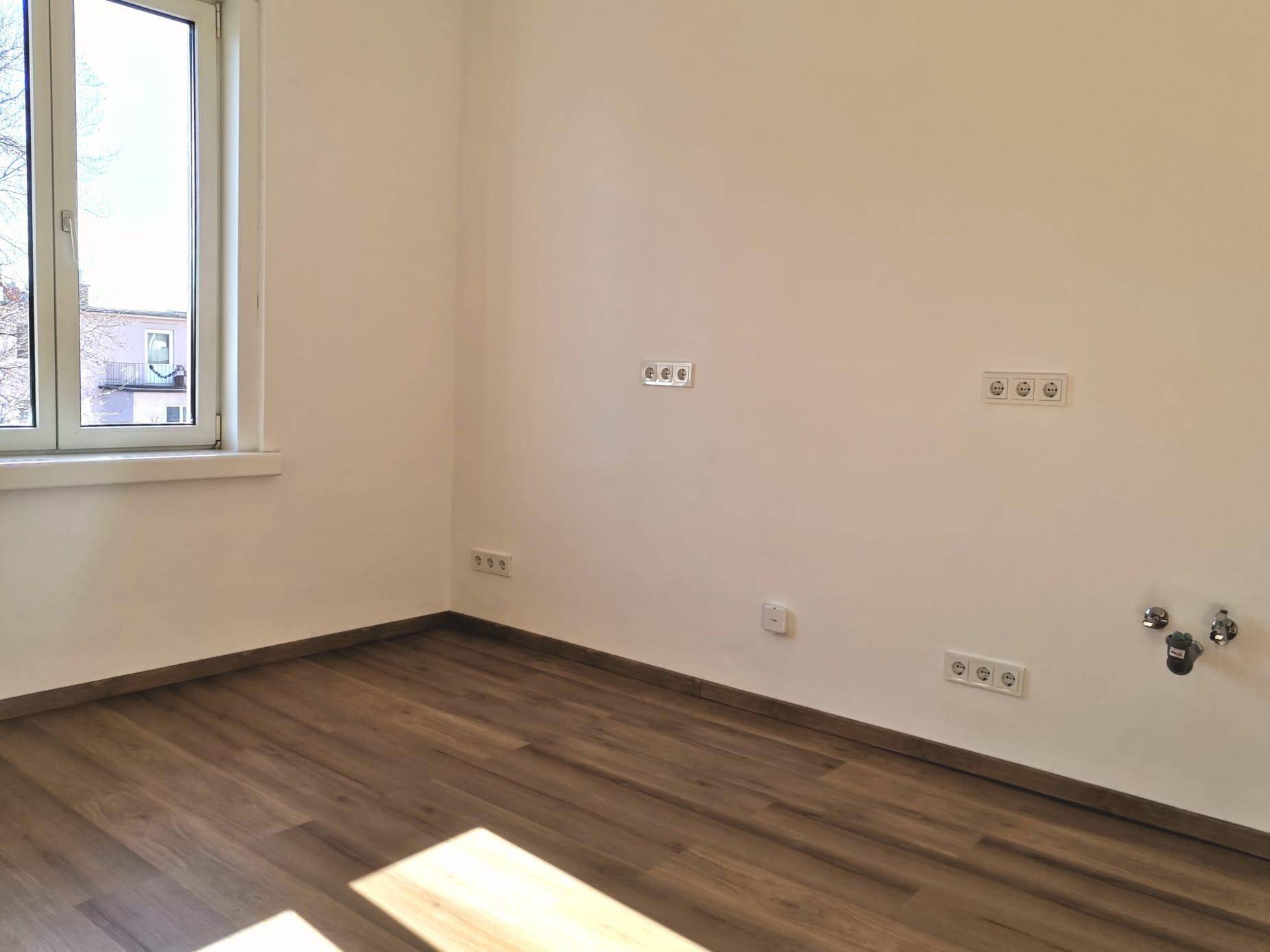 Heller Raum mit modernem Laminatboden und Fenster, bereit für die Installation von Geräten.