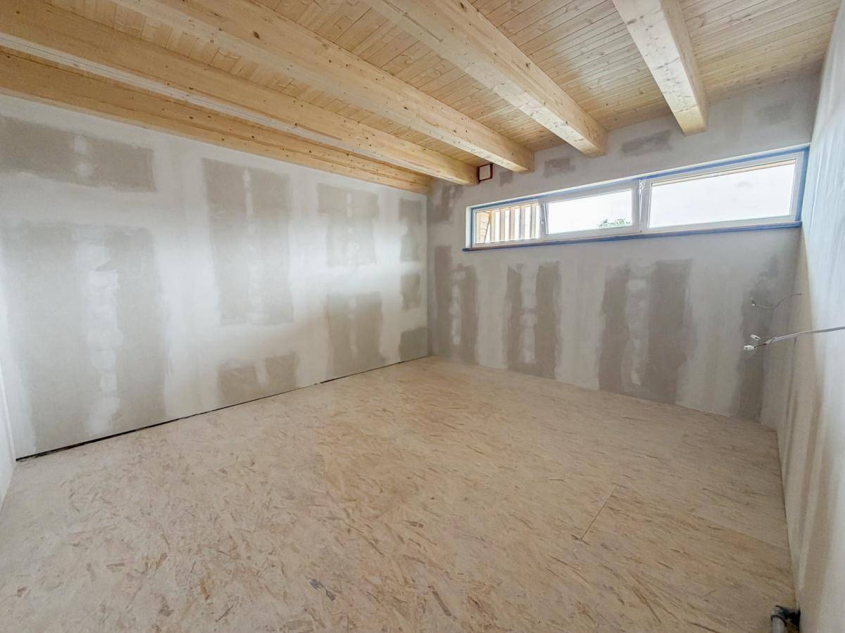 Geräumiger Rohbau mit Holzbalkendecke und Fensterband, bietet viel Potenzial für individuelle Gestaltung.