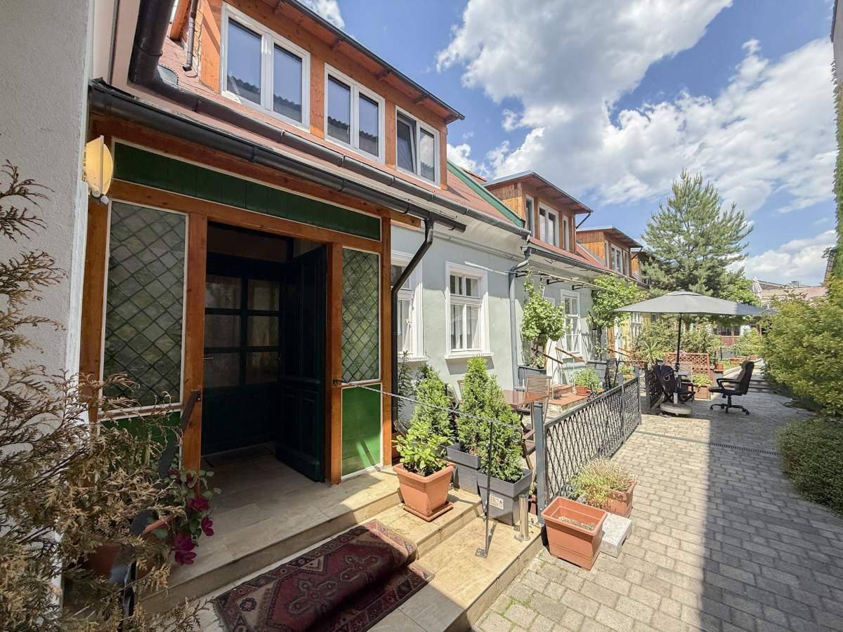 Attraktive Gebäudefassade mit Eingangsbereich, Pflanzen und einer möblierten Terrasse.