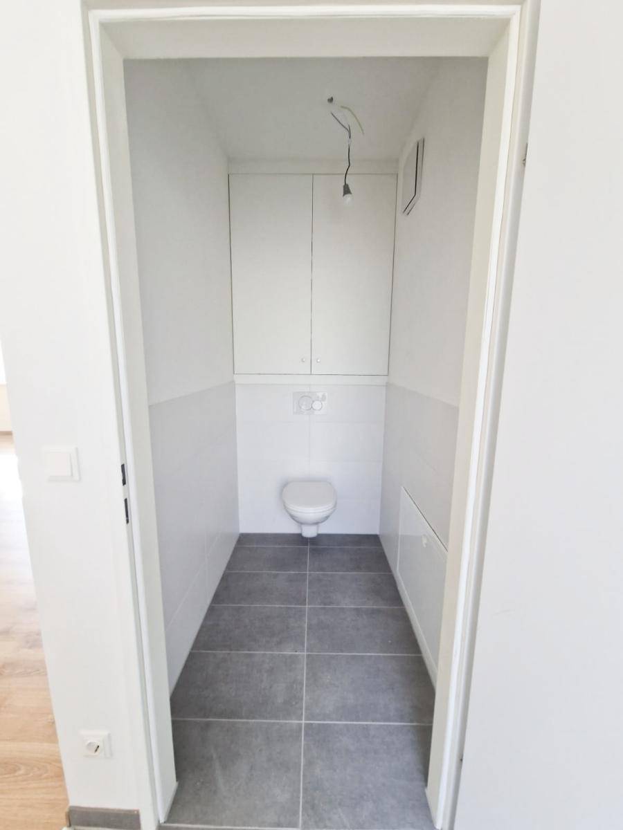 Kleines, modern gefliestes Gäste-WC mit wandhängender Toilette und Einbauschrank.