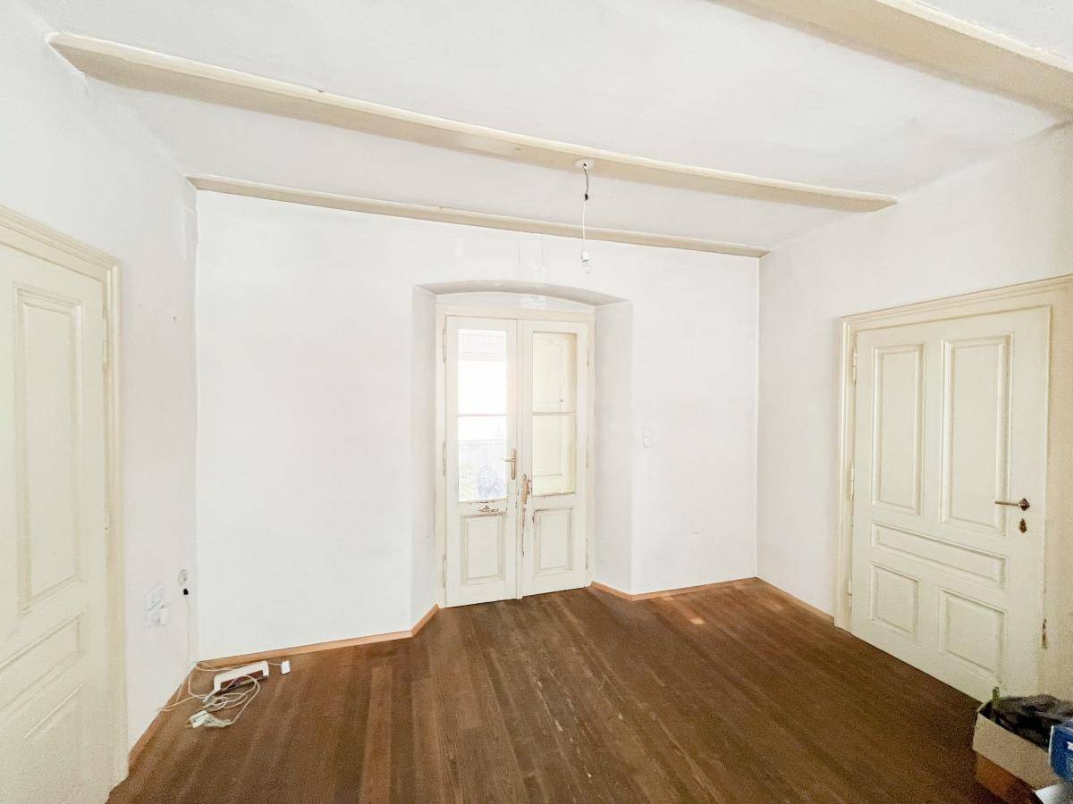 Flur mit Holzboden, hohen Decken und Doppeltüren, die zu weiteren Räumen führen.
