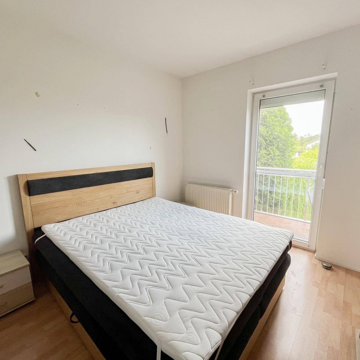 Schlafzimmer mit Doppelbett, Holzboden und Balkonzugang, hell und freundlich.