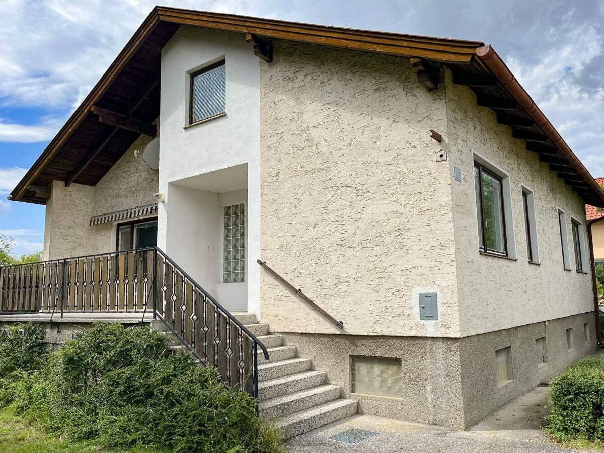 Vorderansicht des Hauses mit Außentreppe, Balkon und heller Putzfassade.