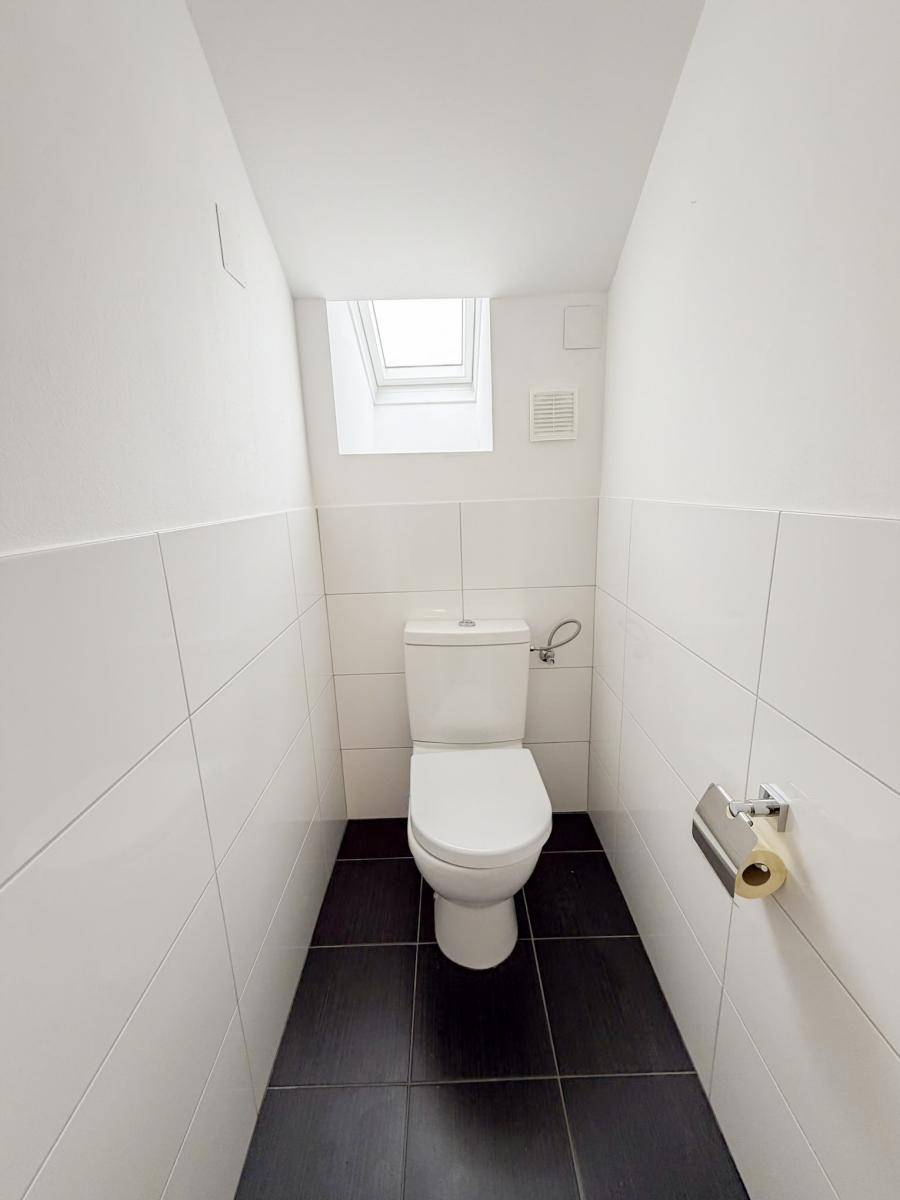 Separates WC mit Fliesenboden und Dachfenster, bietet Privatsphäre.