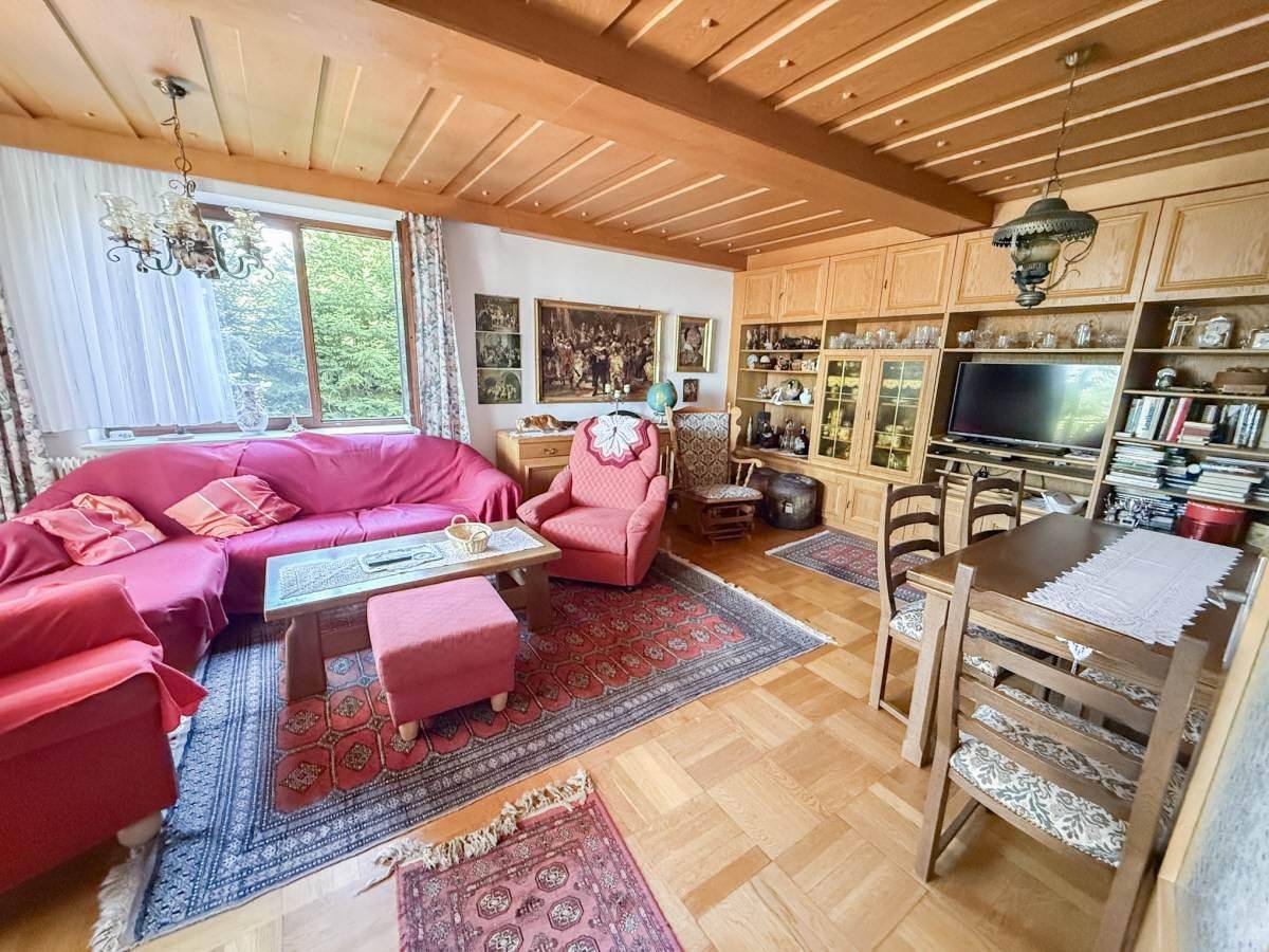 Geräumiger Wohn-Essbereich mit Holzdecke, Parkettboden und traditionellen Möbeln.