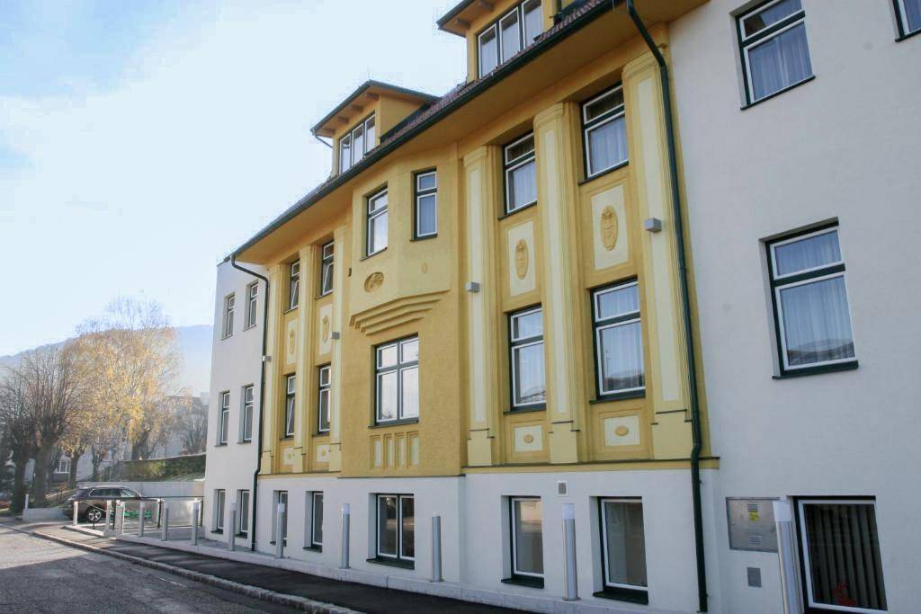 Detailansicht der gelben Fassade mit dekorativen Elementen und vielen Fenstern.