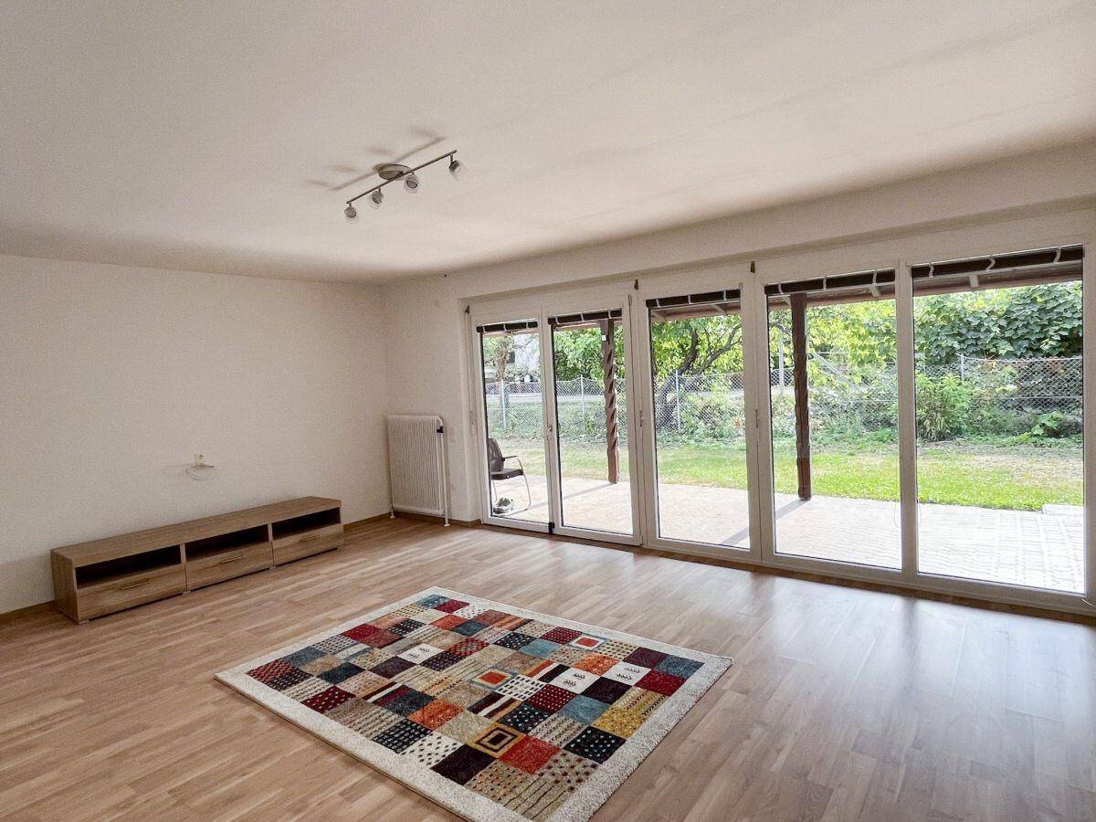 Geräumiges Wohnzimmer mit Laminatboden und breiter Fensterfront zum Garten.