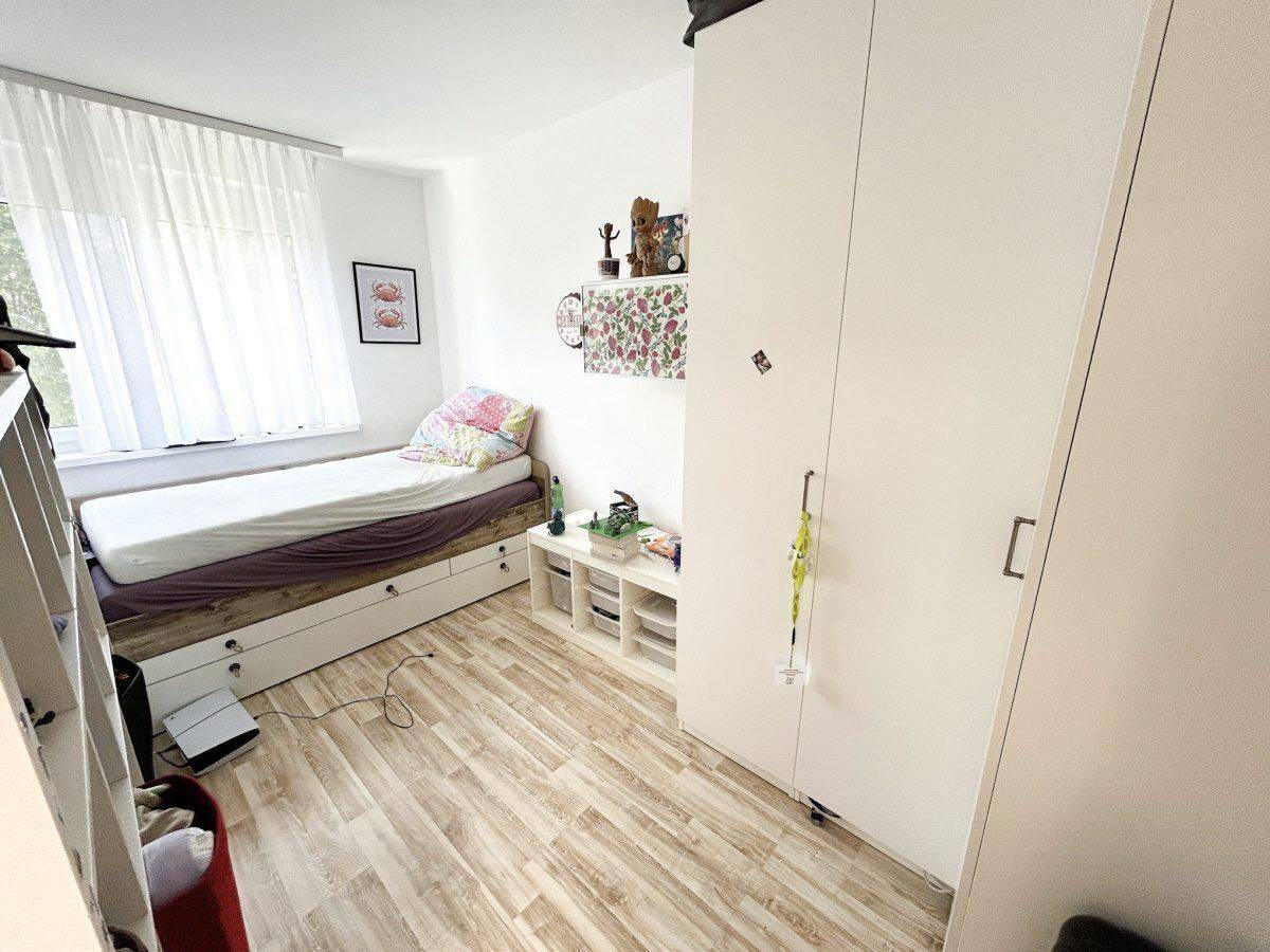 Weiteres Schlafzimmer mit Einzelbett, Kleiderschrank und hellem Holzboden.