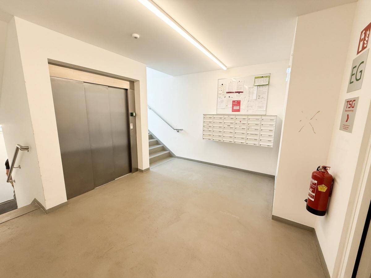 Moderner Eingangsbereich mit Aufzug, Treppe und Briefkästen in einem gepflegten Gebäude.