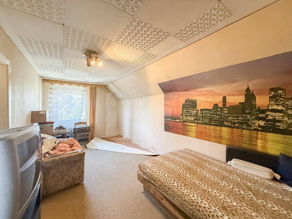 Schlafzimmer im Dachgeschoss mit schrägen Wänden, Teppichboden und Stadtbild-Wandbild.