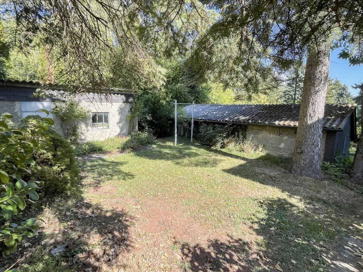 Gartenbereich mit Rasenfläche, Wäscheleine und Nebengebäuden im Hintergrund.