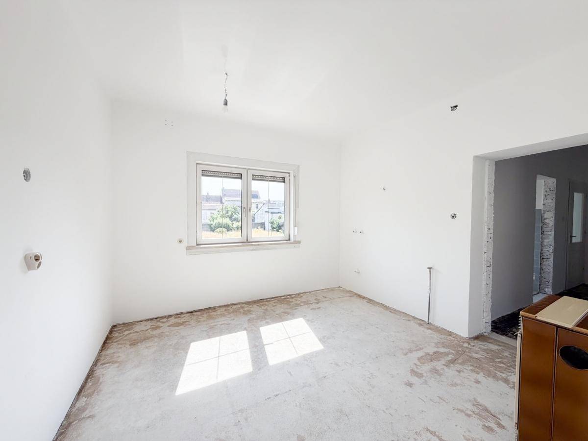 Unmöblierter Raum mit viel Tageslicht und vorbereitetem Boden für weitere Arbeiten.