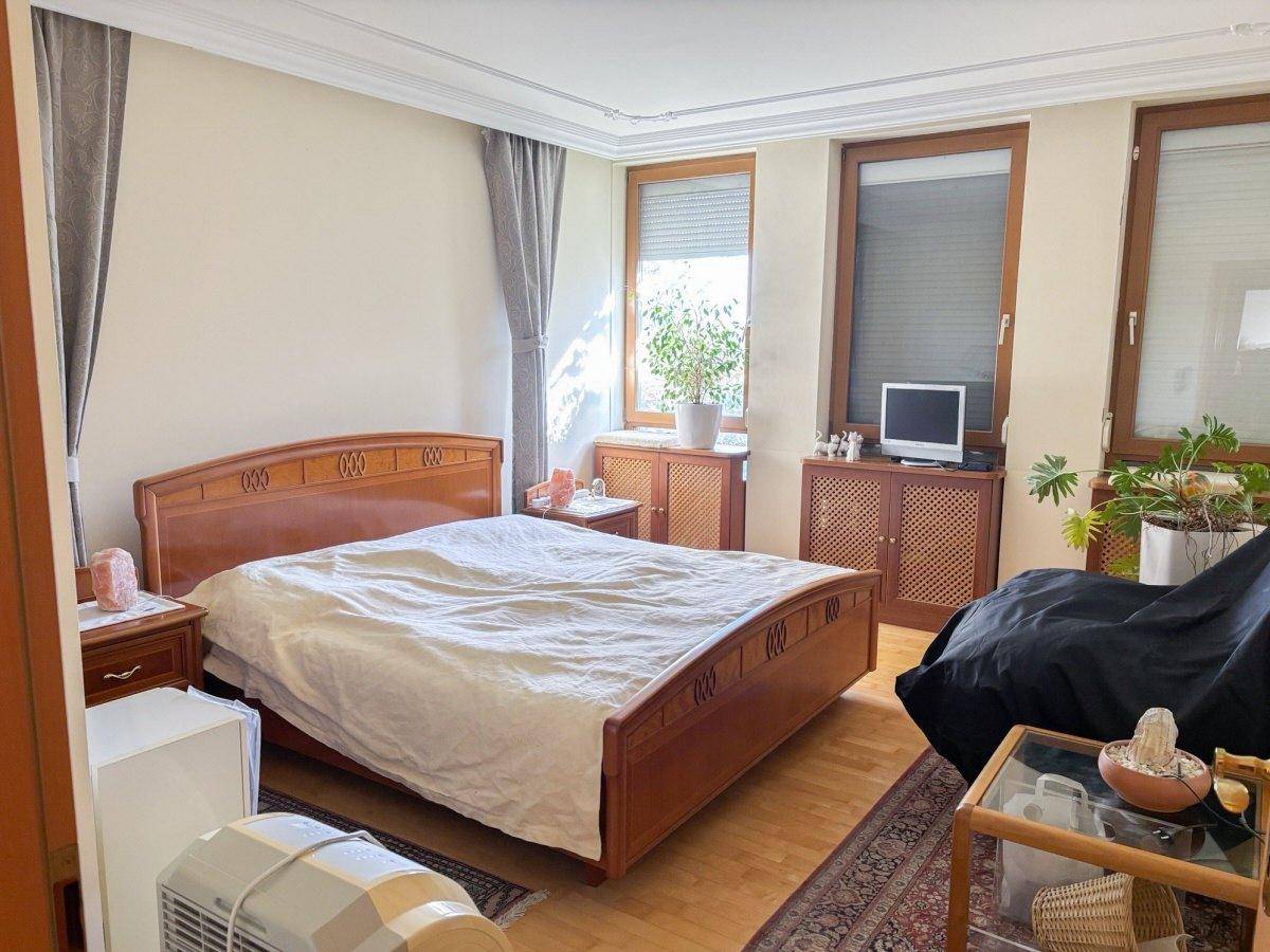 Geräumiges Schlafzimmer mit Holzdoppelbett, Parkettboden und großen Fenstern.
