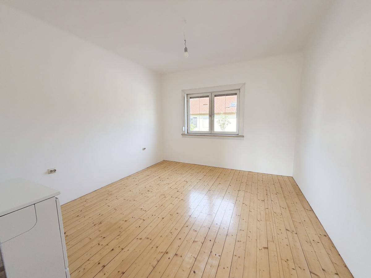 Renovierter Raum mit neu verlegtem Holzdielenboden und hellem Fenster.