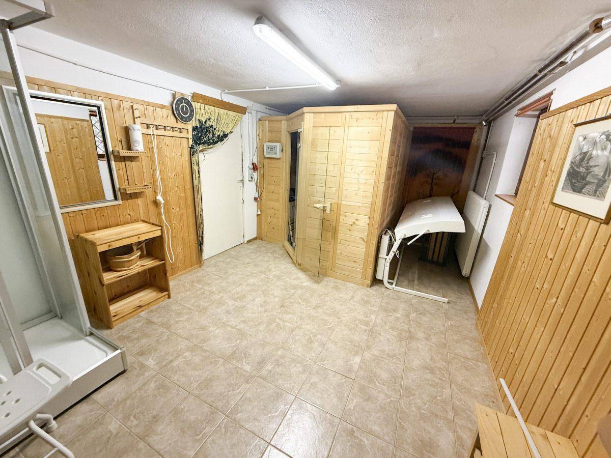 Wellnessbereich mit Holzvertäfelung, Sauna und Duschmöglichkeit.