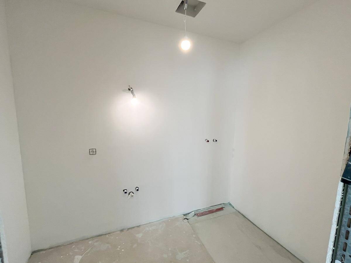 Unfertige Küche mit Anschlüssen für Spüle und Geräte, bereit für den Einbau.