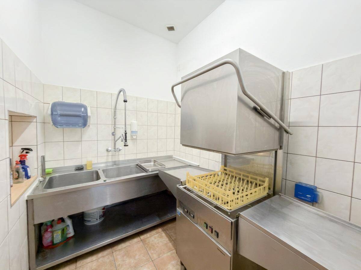 Spülbereich einer Großküche mit doppelten Edelstahlspülbecken und gewerblichem Geschirrspüler.