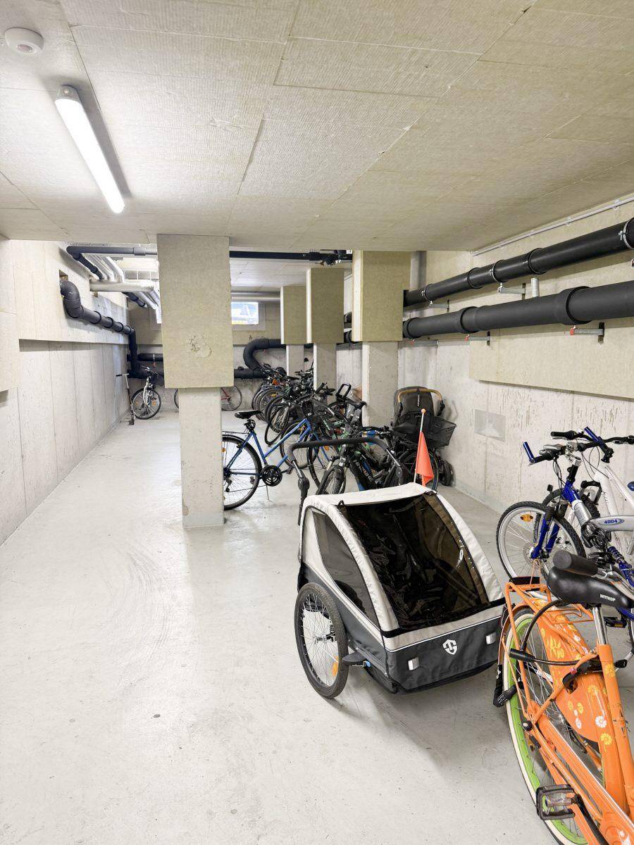 Geräumiger Fahrradraum im Untergeschoss mit vielen Fahrrädern und Kinderanhänger.