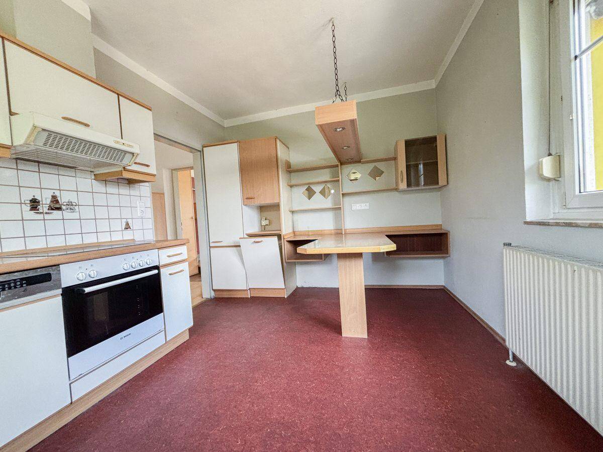 Geräumige Küche mit Essbereich, weißen Schränken und Fenster für viel Tageslicht.
