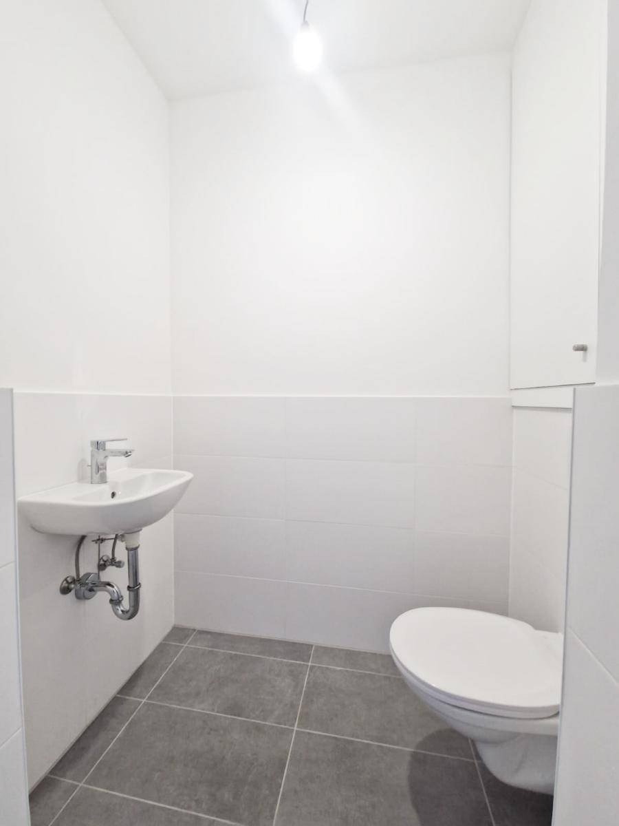 Kleines, helles Gäste-WC mit wandmontierter Toilette und Waschbecken.
