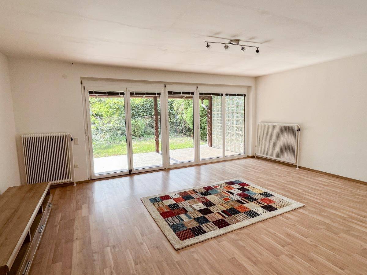 Helles Wohnzimmer mit Laminatboden, großen Fenstern und Zugang zum Garten.