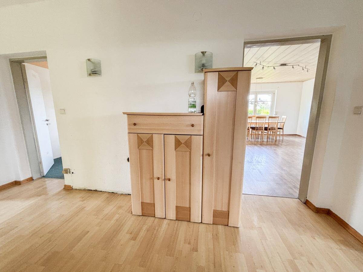 Flur mit Laminatboden und Holzschrank, der zum Essbereich führt.
