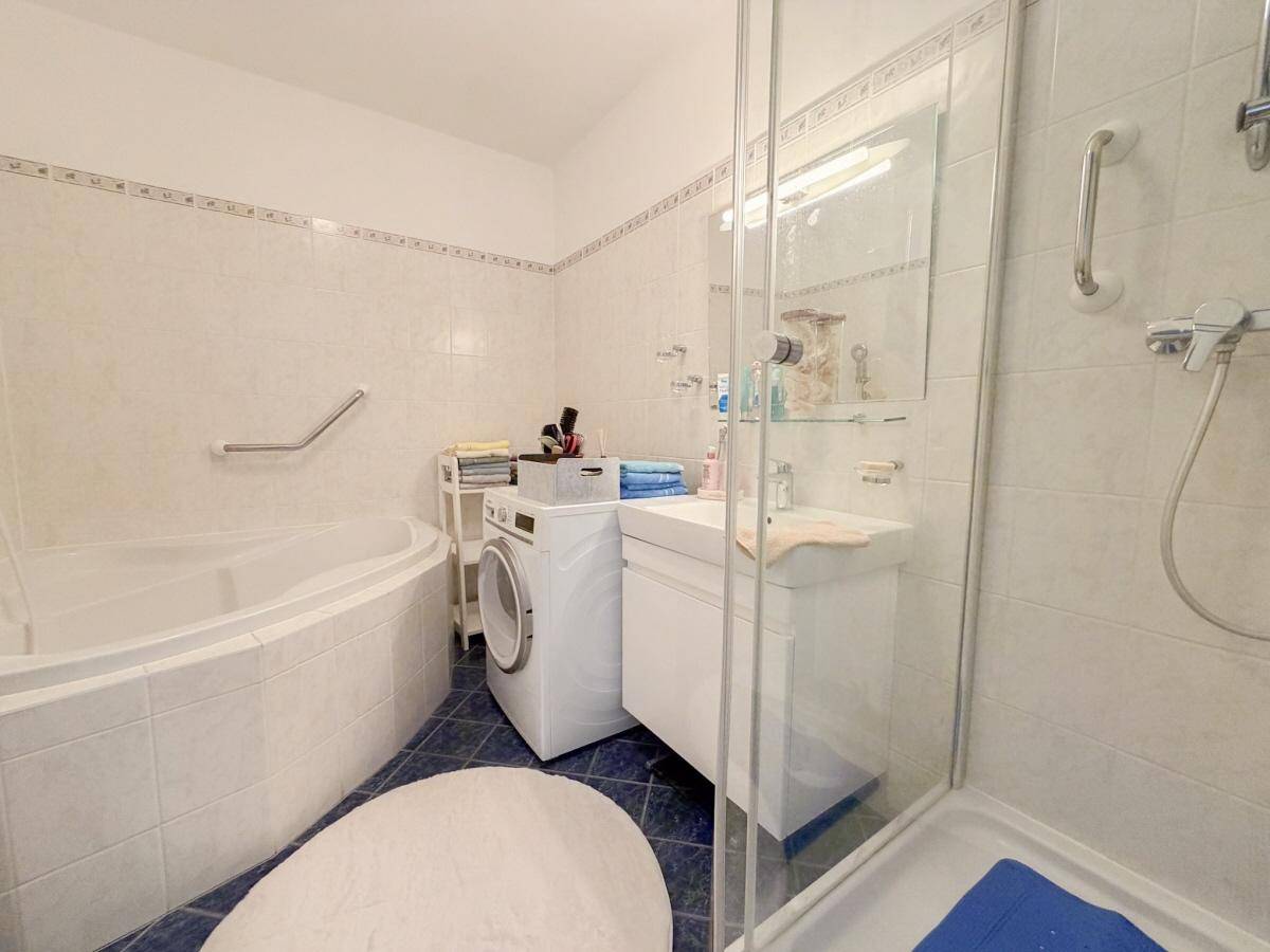 Badezimmer mit Eckbadewanne, Duschkabine, Waschbecken und Waschmaschine.