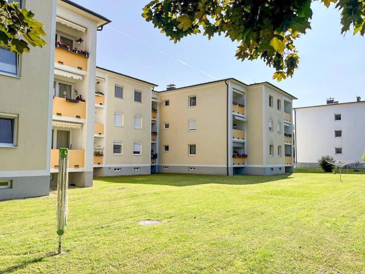 Wohngebäude mit großem Rasenbereich und Bäumen, ideal für Erholung im Freien.