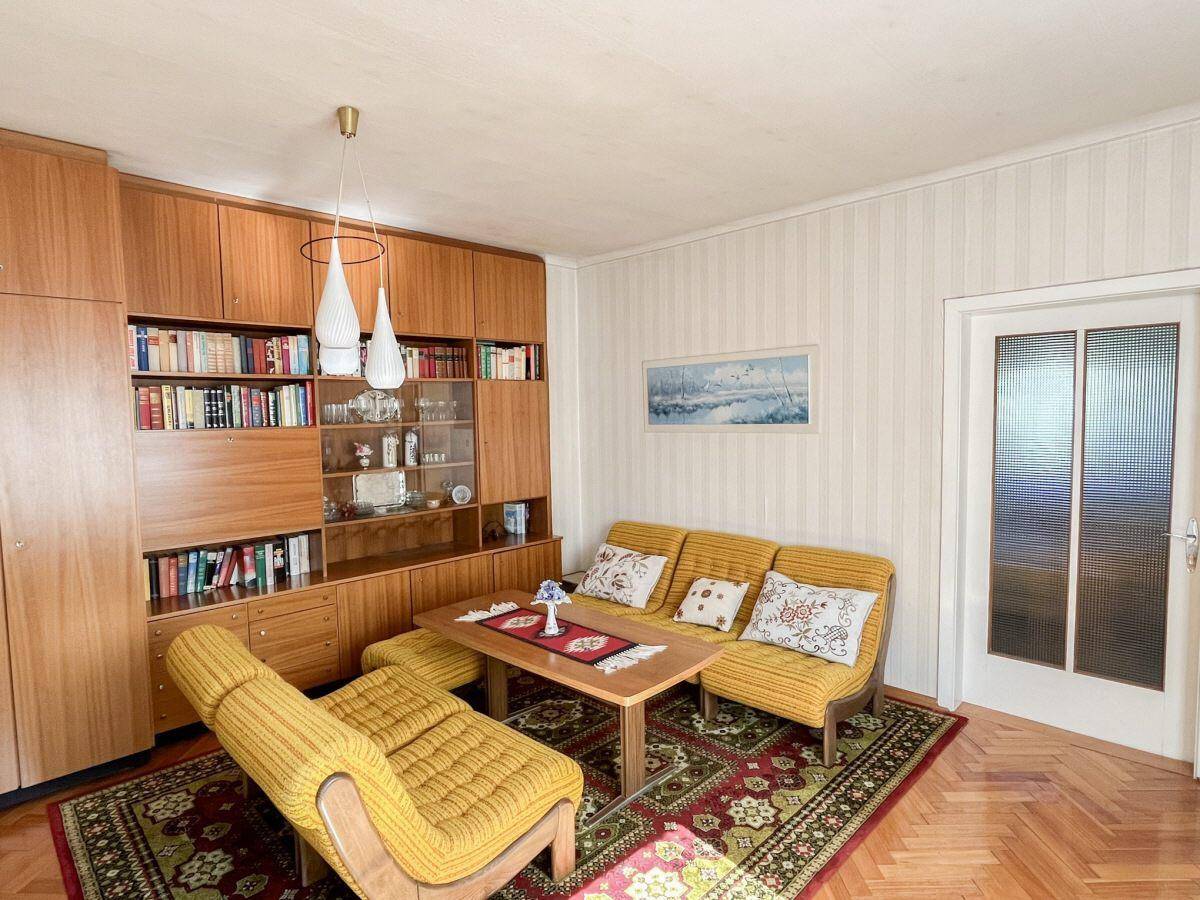 Wohnzimmer mit großem Holzregal, bequemen Sitzmöbeln und Parkettboden.