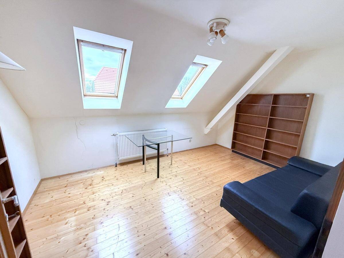 Dachgeschosszimmer mit Holzboden, Dachfenstern und viel natürlichem Licht.
