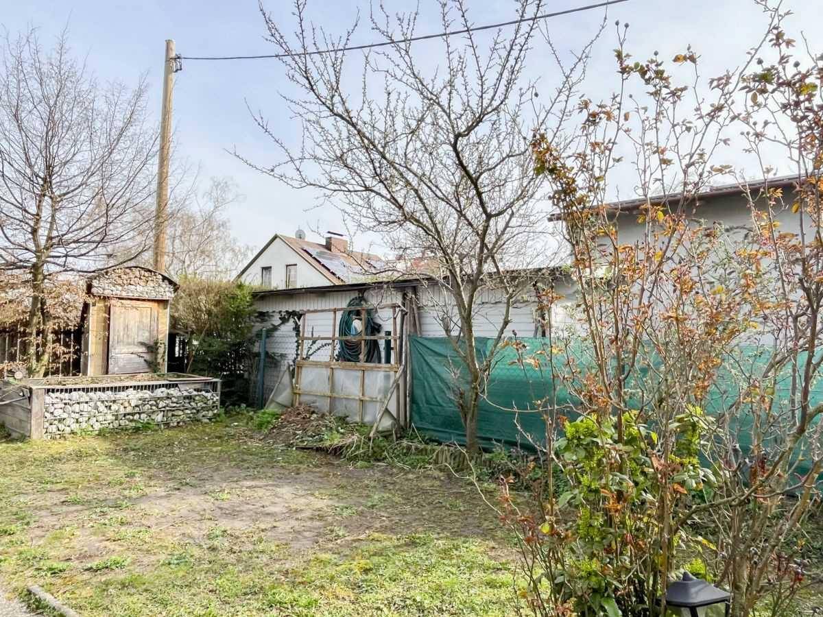 Gartenbereich mit Rasenfläche, Bäumen und einem kleinen Holzschuppen.
