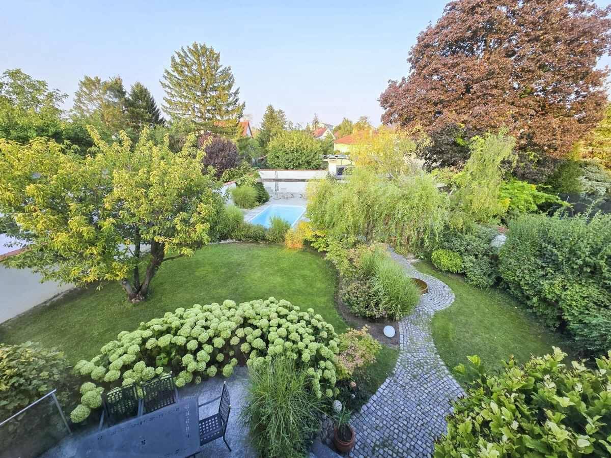 Weitläufiger Garten mit Pool, großer Rasenfläche und verschiedenen Pflanzenbereichen aus der Vogelperspektive.