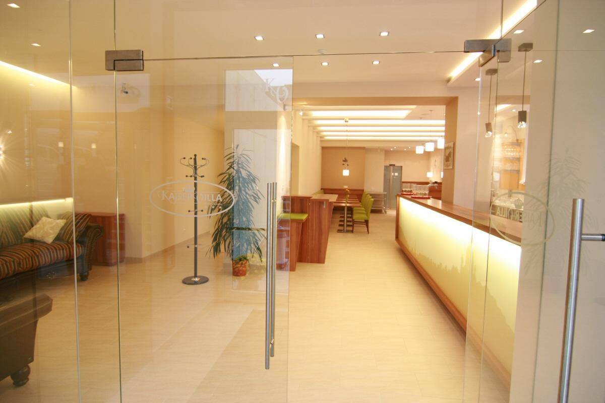 Heller Eingangsbereich mit Glastüren, Rezeption und Blick in den Speisesaal.