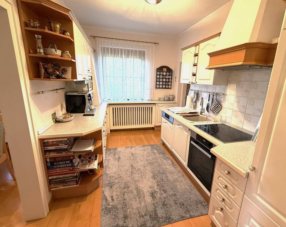 Funktionale Küche mit weißen Schränken, Fliesenrückwand und Fenster für Tageslicht.