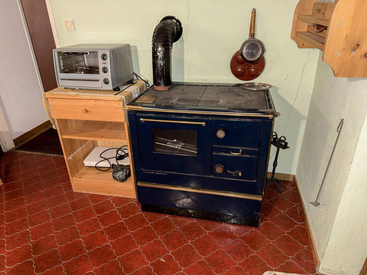 Traditioneller Holzofen mit Backfach und Kochplatten in rustikaler Küche.