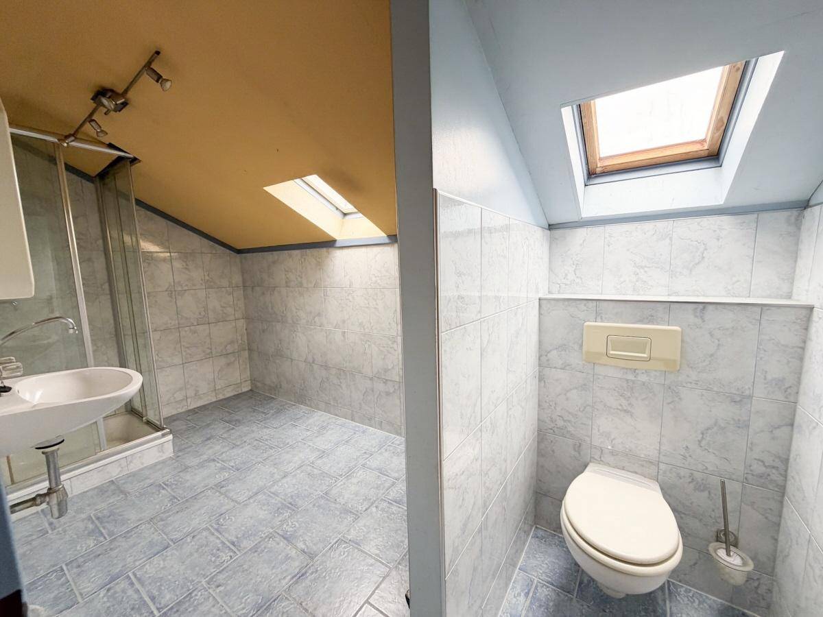 Badezimmer im Dachgeschoss mit Dusche, WC, Waschbecken und Dachfenster.