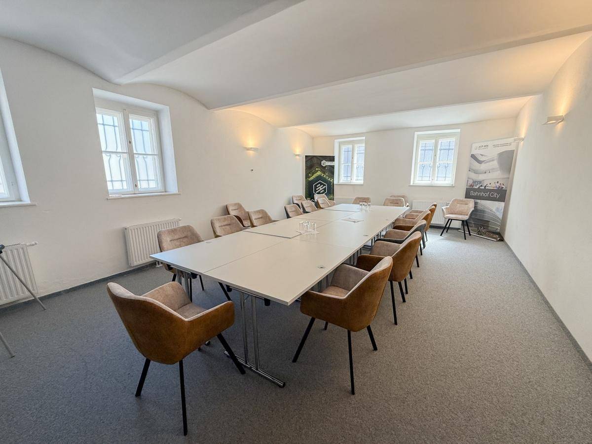 Großer Konferenzraum mit Teppichboden, langer Tafel und vielen Stühlen für Besprechungen.