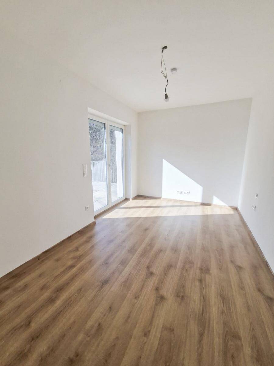 Helles Zimmer mit Laminatboden und Zugang zu einem Balkon, ideal als Schlafzimmer.