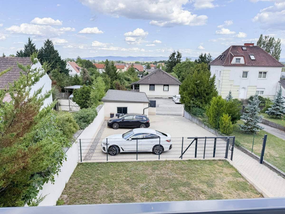 Blick von oben auf den gepflasterten Hof mit zwei Autos und einer Garage.