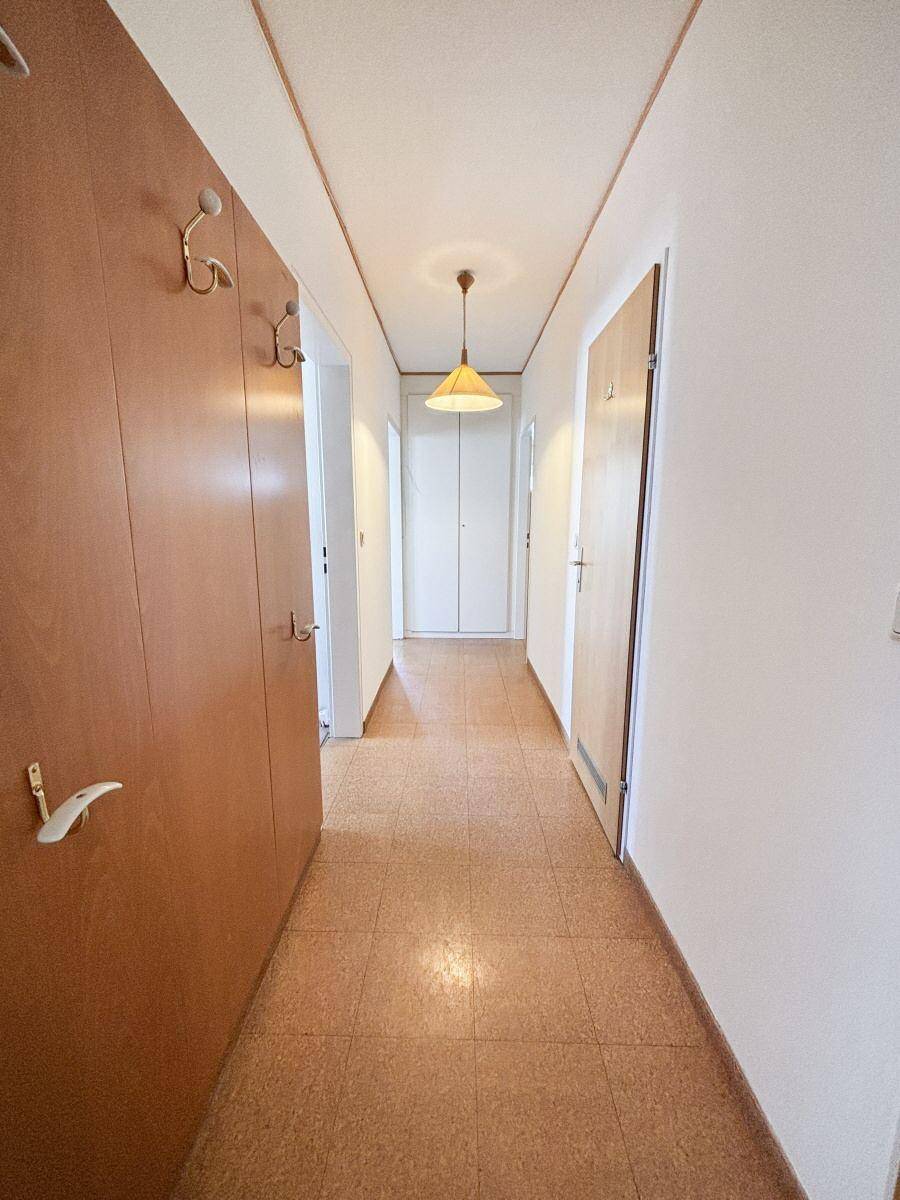 Langer Flur mit Korkboden und Garderobe, der zu weiteren Räumen führt.