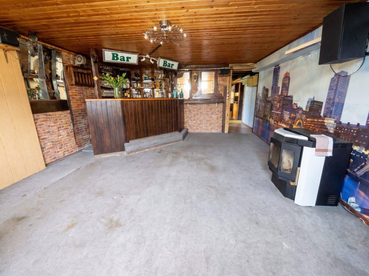 Großer Hobbyraum im Keller mit Bar, Holzdecke und Kaminofen.