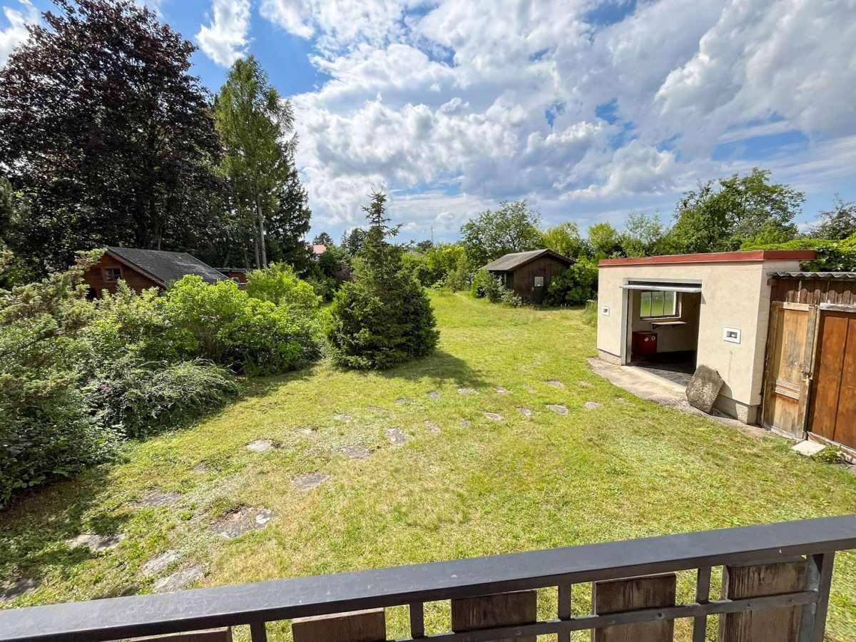 Großer Garten mit Rasenfläche, Garage und Schuppen, von einem Balkon aus gesehen.