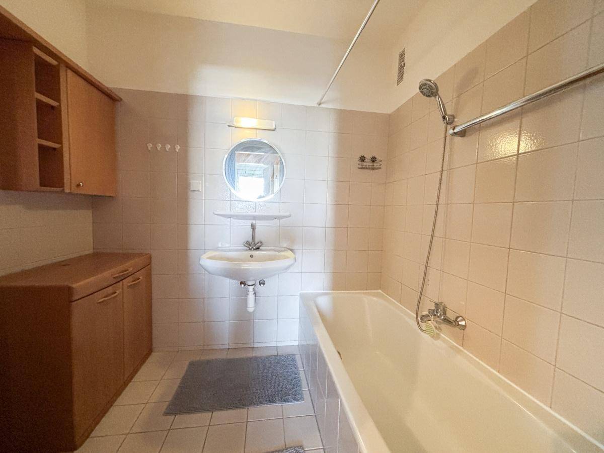 Badezimmer mit beigefarbenen Fliesen, Badewanne und Waschbecken.