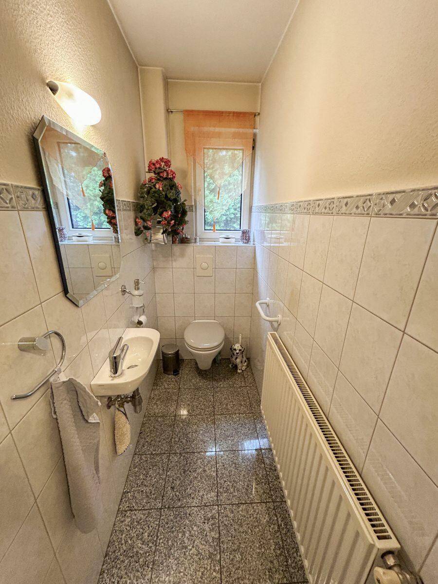 Kleines Gäste-WC mit Waschbecken, Toilette und hell gefliesten Wänden.