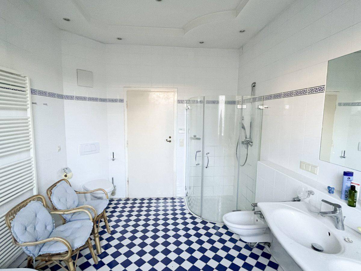 Helles Badezimmer mit blauen und weißen Fliesen, Dusche, WC und Bidet.