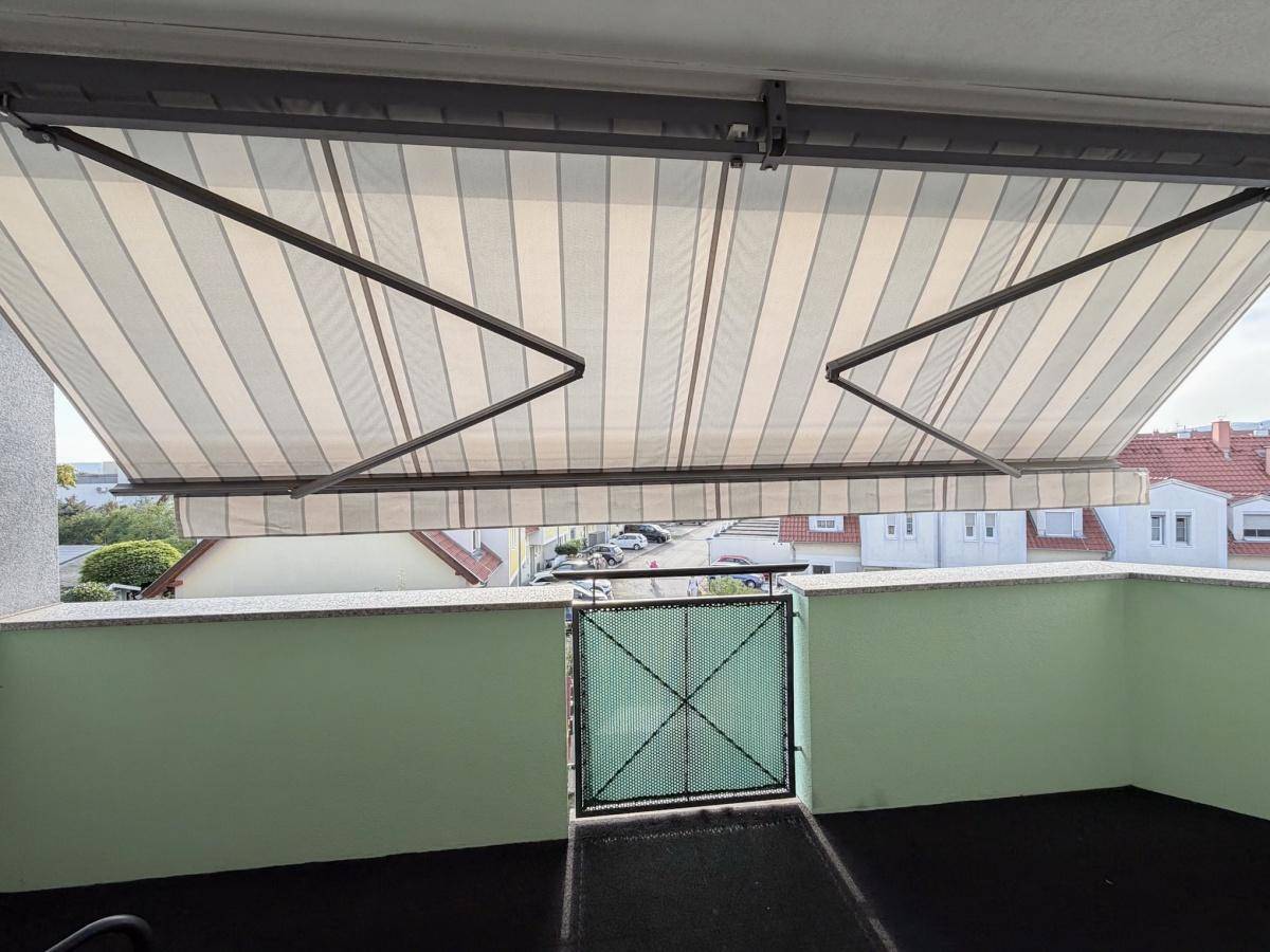 Balkon mit ausgefahrener Markise bietet Schutz vor der Sonne.